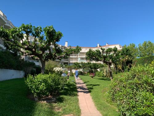 people walking down a path in a park with trees at Studio de standing climatisé, avec piscine, proche de la mer in Fréjus