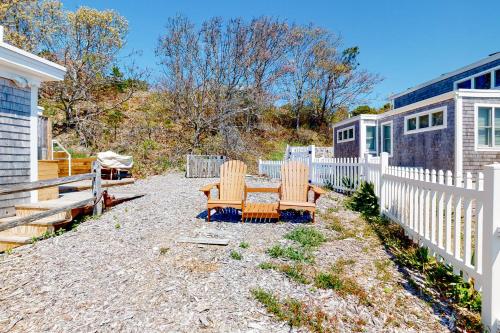 a patio with two chairs and a bench next to a fence at Dunes Edge in Wellfleet