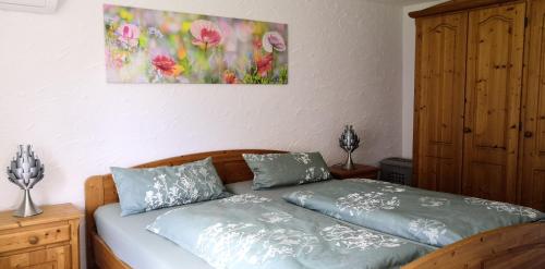 1 cama con 2 almohadas y una pintura en la pared en Ferienhaus Diana im Harz, en Mansfeld