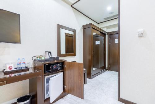 um quarto com um lavatório e um balcão com um micro-ondas em Qushbegi Plaza Hotel em Tashkent
