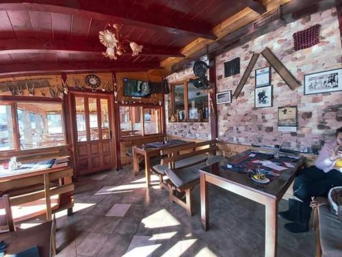 a room with wooden tables and a stone wall at Hotel Lovac in Žabljak