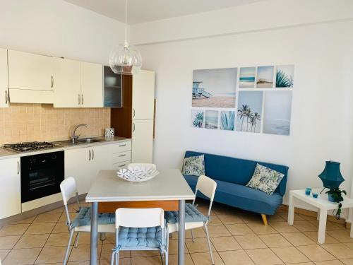 a kitchen and living room with a table and a blue couch at Emilio's in Marina di Ragusa