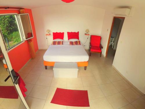 a bedroom with a bed and two red chairs at Appartement Camillia, 41m2 et son jardin privatif. in Petit-Bourg