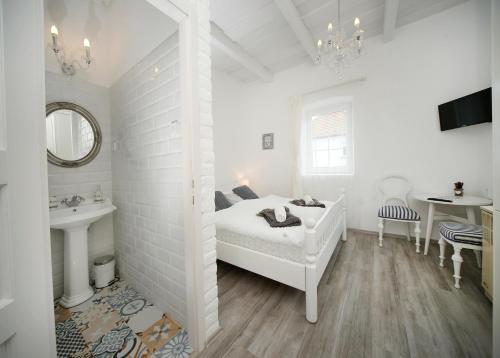 a white bedroom with a bed and a sink at Vidéki Varázs Vendégház in Bogács