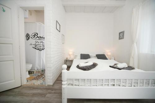 a white bedroom with a white bed and a bathroom at Vidéki Varázs Vendégház in Bogács