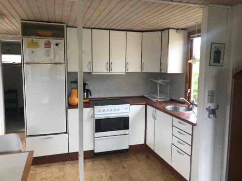 a kitchen with white cabinets and a white refrigerator at The Beach House in Haderslev