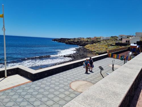 two people standing on a walkway looking at the ocean at Casa rural meridiano in El Pinar del Hierro