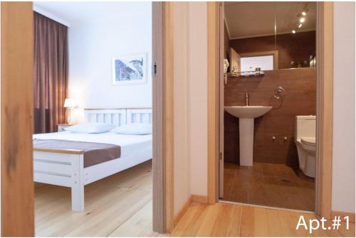 1 dormitorio con 1 cama y baño con lavamanos en svaneti apartment's, en Mestia