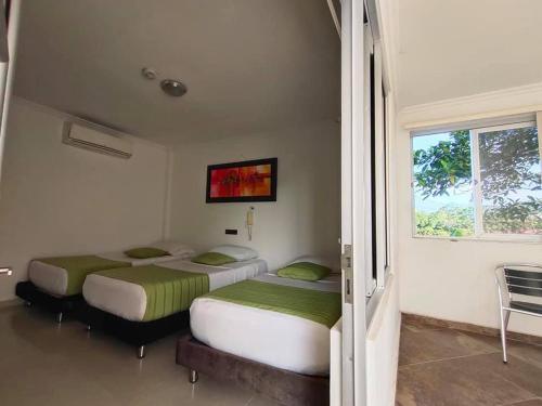 two twin beds in a room with a window at Confort Plaza Hotel in Villavicencio