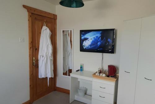 a bathroom with a tv on the wall and a door at Comfy House in Portstewart