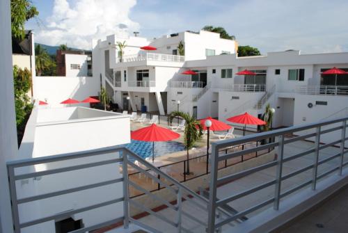 a balcony with red umbrellas and a swimming pool at Apartamento Quinta Avenida in Melgar