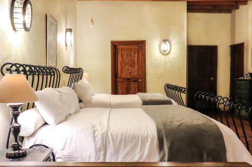 a bedroom with two beds with white sheets and a lamp at Mirador del Frayle in San Miguel de Allende