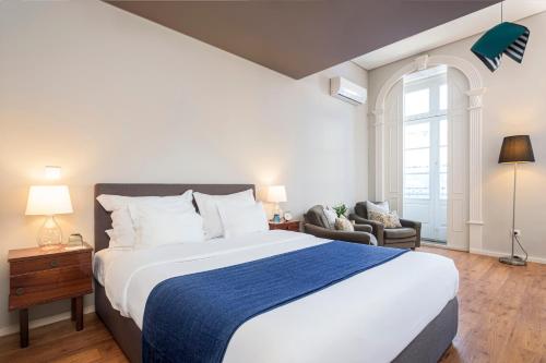 een slaapkamer met een groot bed en een blauwe deken bij B The Guest Downtown in Porto