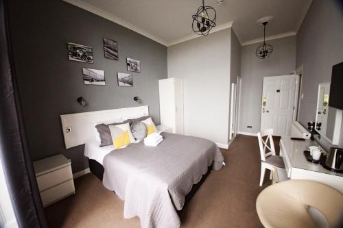 um quarto com uma cama branca e uma cadeira em The Lansdowne em Hastings