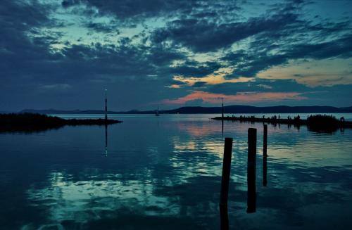 a sunset over a body of water with poles in the water at Villa Aquamarine in Balatonboglár