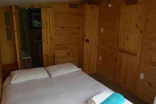 a bedroom with a white bed with wooden walls at La Frontera Bed & Breakfast, Valle Cochamó in Cochamó