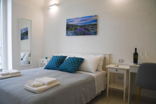 Schlafzimmer mit einem Bett mit blauen Kissen und einem Schreibtisch in der Unterkunft B&B Benefici in Maruggio