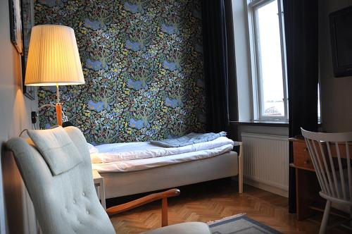 a bedroom with a bed and a lamp and a chair at Laholms Stadshotell in Laholm