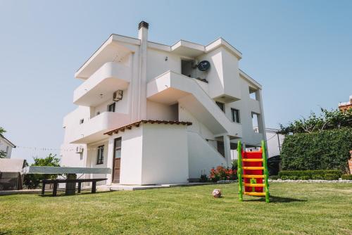 un edificio blanco con un parque infantil delante de él en Apartments Radosevic, en Ulcinj
