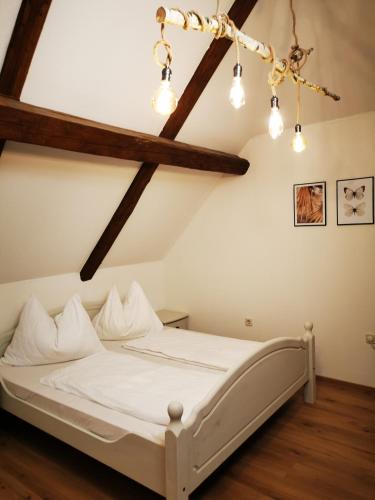 a bedroom with a white bed with wooden beams at Stadl Suite in Sankt Margarethen im Lavanttal