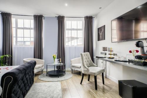 a living room with a couch and chairs and a kitchen at Villare Leicester City Centre hotel in Leicester