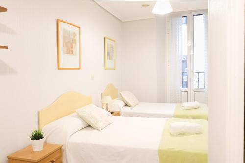 Una habitación blanca con dos camas y una ventana. en Pensión San Lorenzo, en San Sebastián