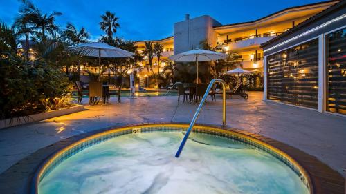 a jacuzzi tub in a courtyard with tables and umbrellas at The Encinitan Hotel & Suites in Encinitas