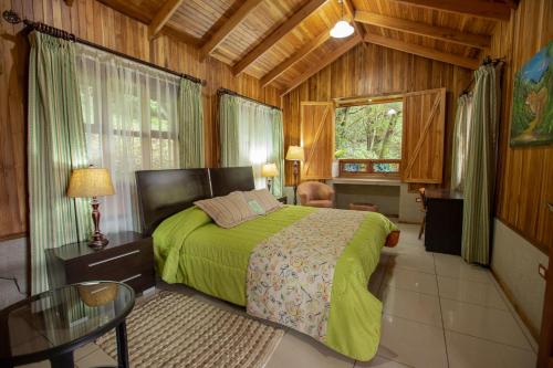 um quarto com uma cama verde num quarto de madeira em Los Pinos Cabins & Reserve em Monteverde