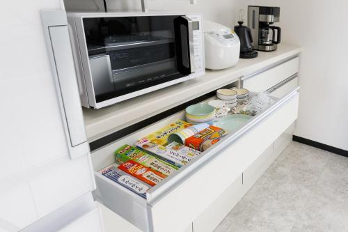 a refrigerator with a microwave and food in it at オーシャンビューFORTUNA YAKA Ace 12名対応 海まで徒歩 シャワールーム 2 BBQ OK in Kin