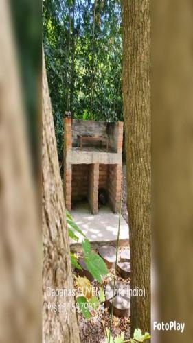 a bench sitting between two trees in a forest at Cabañas Cuyen in Punta Indio