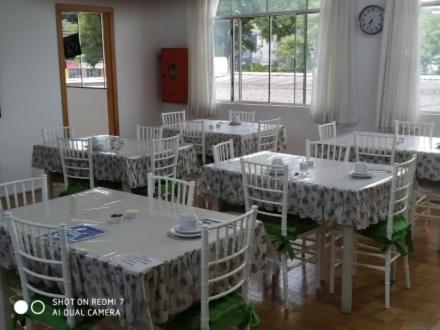 uma sala de jantar com mesas brancas e cadeiras brancas em Hotel Iguaçu Chapecó em Chapecó