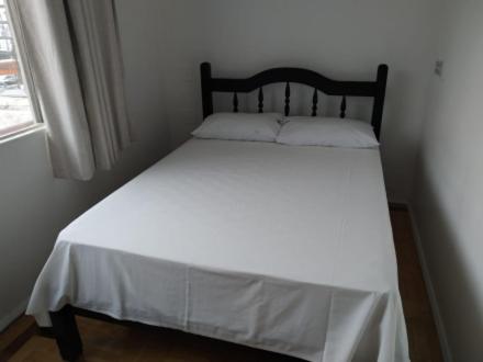 un letto in una camera da letto con lenzuola bianche e finestra di Hotel Iguaçu Chapecó a Chapecó