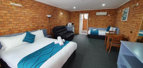 ein Schlafzimmer mit einem Bett, einem Stuhl und einem Tisch in der Unterkunft Centrepoint Motel Deniliquin in Deniliquin