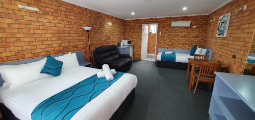 a bedroom with a bed and a chair and a table at Centrepoint Motel Deniliquin in Deniliquin