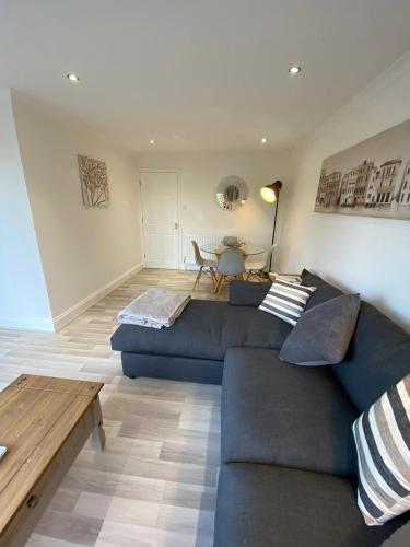 a living room with a blue couch and a table at Penthouse Waterfront Apartment - St Neots in Saint Neots
