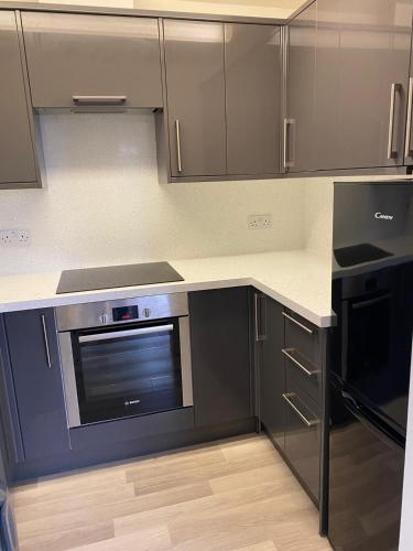 a kitchen with a stove and a microwave at Penthouse Waterfront Apartment - St Neots in Saint Neots