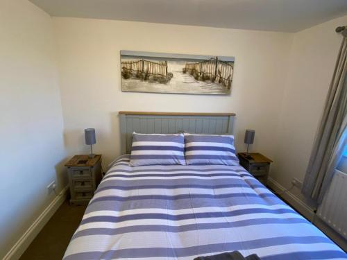 a bedroom with a bed with blue and white stripes at Penthouse Waterfront Apartment - St Neots in Saint Neots