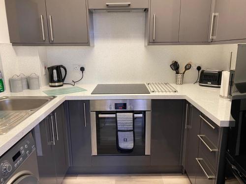 a kitchen with a stove and a microwave in it at Penthouse Waterfront Apartment - St Neots in Saint Neots