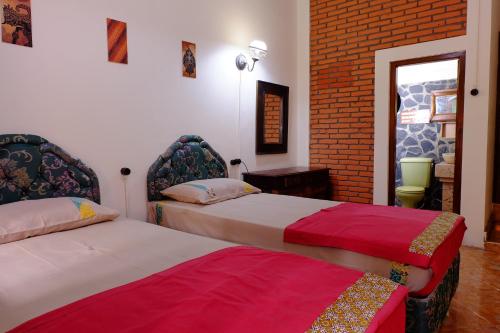 sypialnia z 2 łóżkami i ceglaną ścianą w obiekcie Kampoeng Djawa Hotel w mieście Yogyakarta