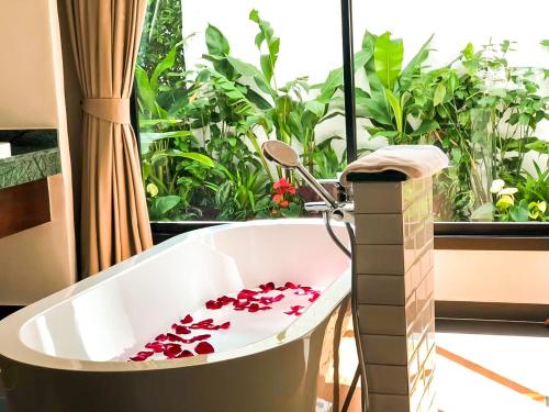 a bath tub with flowers in a room with a window at Smile Lanna Hotel in Chiang Mai