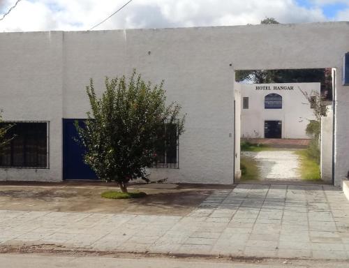 a white building with a tree in front of it at Hotel Hangar in Bagé
