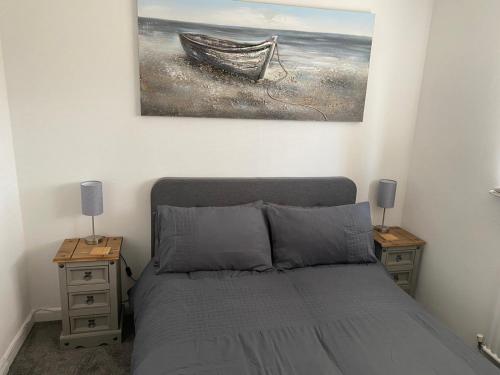 a bedroom with a bed with two nightstands and a painting at Riverside Park Ground Floor Apartment - St Neots in Saint Neots