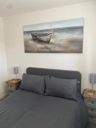 a bedroom with a bed and a painting of a boat at Riverside Park Ground Floor Apt 1 BR Parking St Neots in Saint Neots