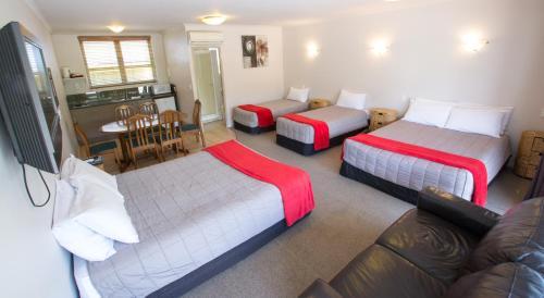 a room with two beds and a couch and a kitchen at Absolute Lake View Motel in Taupo
