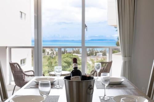 a table with a bottle of wine on a table with glasses at オーシャンビューFORTUNA YAKA Ace 12名対応 海まで徒歩 シャワールーム 2 BBQ OK in Kin