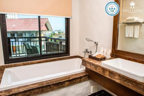 a bathroom with a bath tub and a window at Smile Lanna Hotel in Chiang Mai