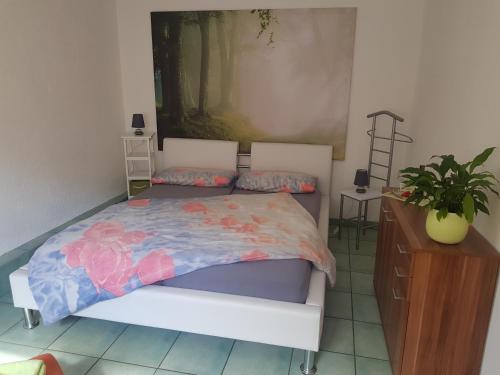 - une chambre avec un lit, une plante et une commode dans l'établissement Ferienwohnung Burgenblick, à Thale