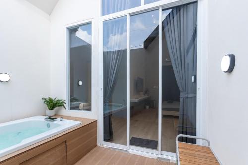 a bathroom with a tub and a large window at Nidhra นิทรา in Ban Lat Krachaeng