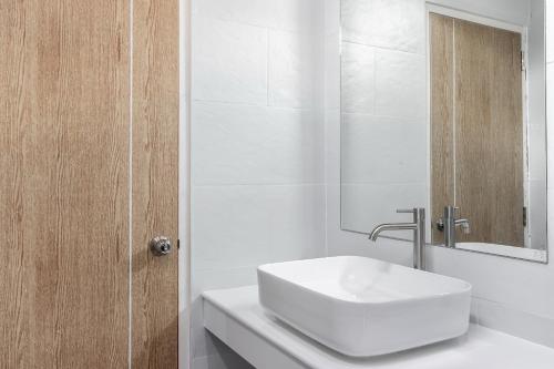 a white bathroom with a sink and a mirror at Nidhra นิทรา in Ban Lat Krachaeng