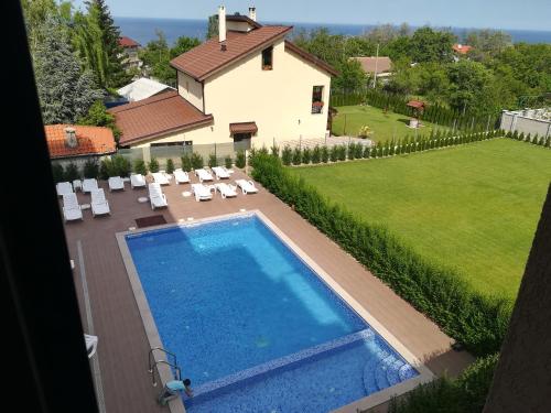 a swimming pool in front of a house with a yard at Hotel Vanilla, Varna - Free parking in Varna City